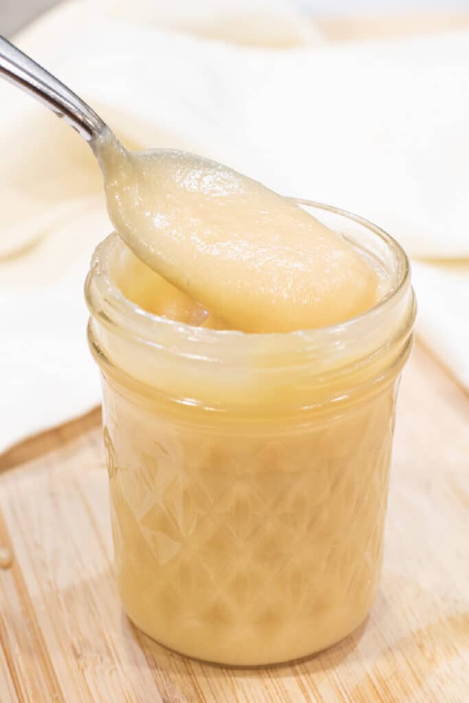 an open mason jar of condensed milk with a spoon.