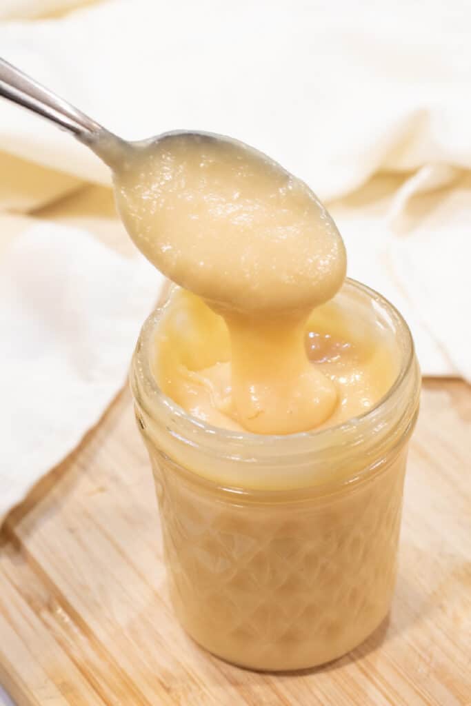 an open mason jar of condensed milk with a spoon.