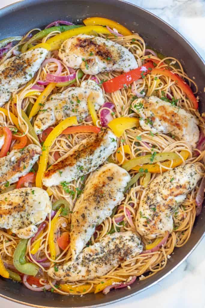 a large pan with cooked chicken tenders, peppers, and pasta.