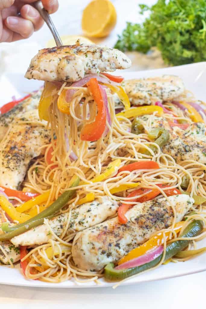 a large platter of chicken, peppers, and pasta with a fork holding a serving up.