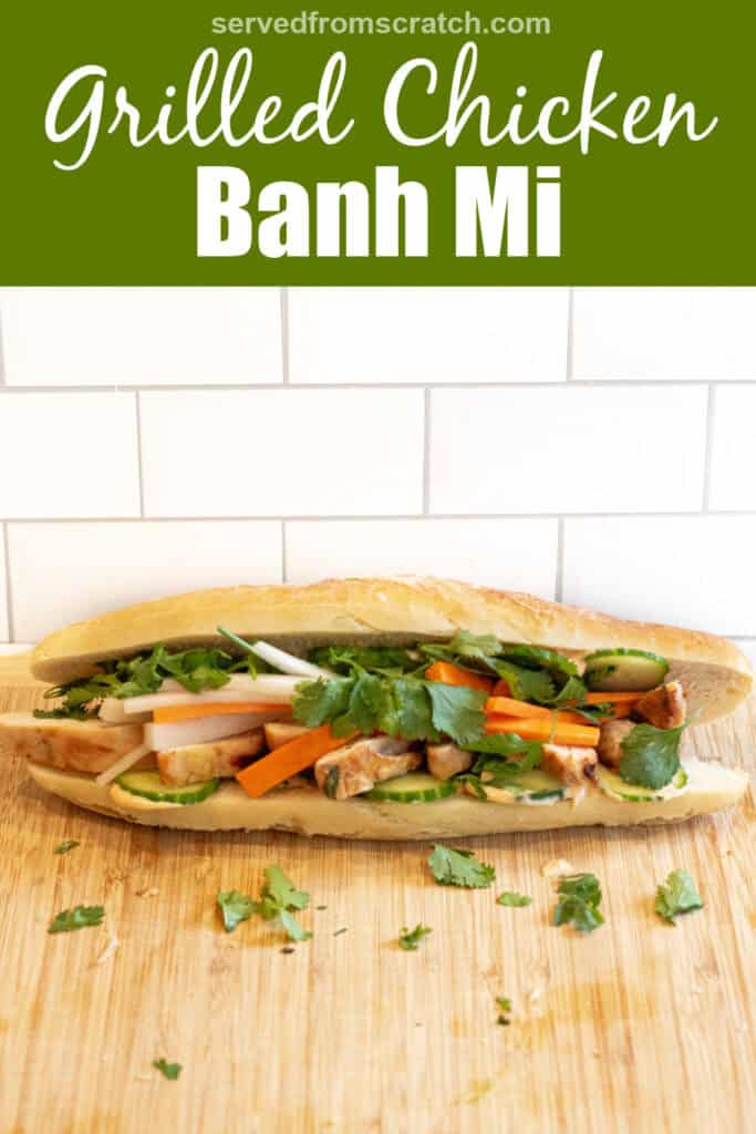 a chicken banh mi sandwich with cucumbers and carrots and cilantro on a cutting board with Pinterest pin text.