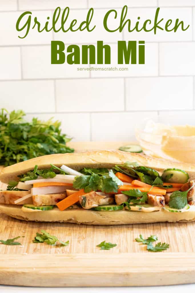 a chicken banh mi sandwich with cucumbers and carrots and cilantro on a cutting board with Pinterest pin text.