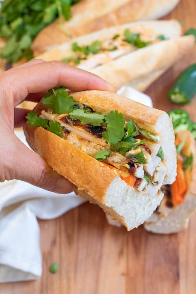 a hand holding a half of a banh mi sandwich.