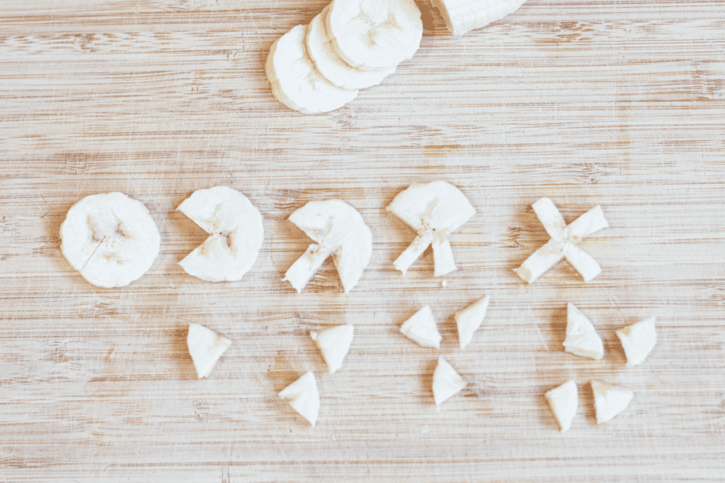 sliced bananas on cutting board, 4 with pieces cut out to make Xs.