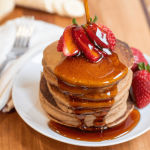 a stack of pancakes with syrup being poured on.
