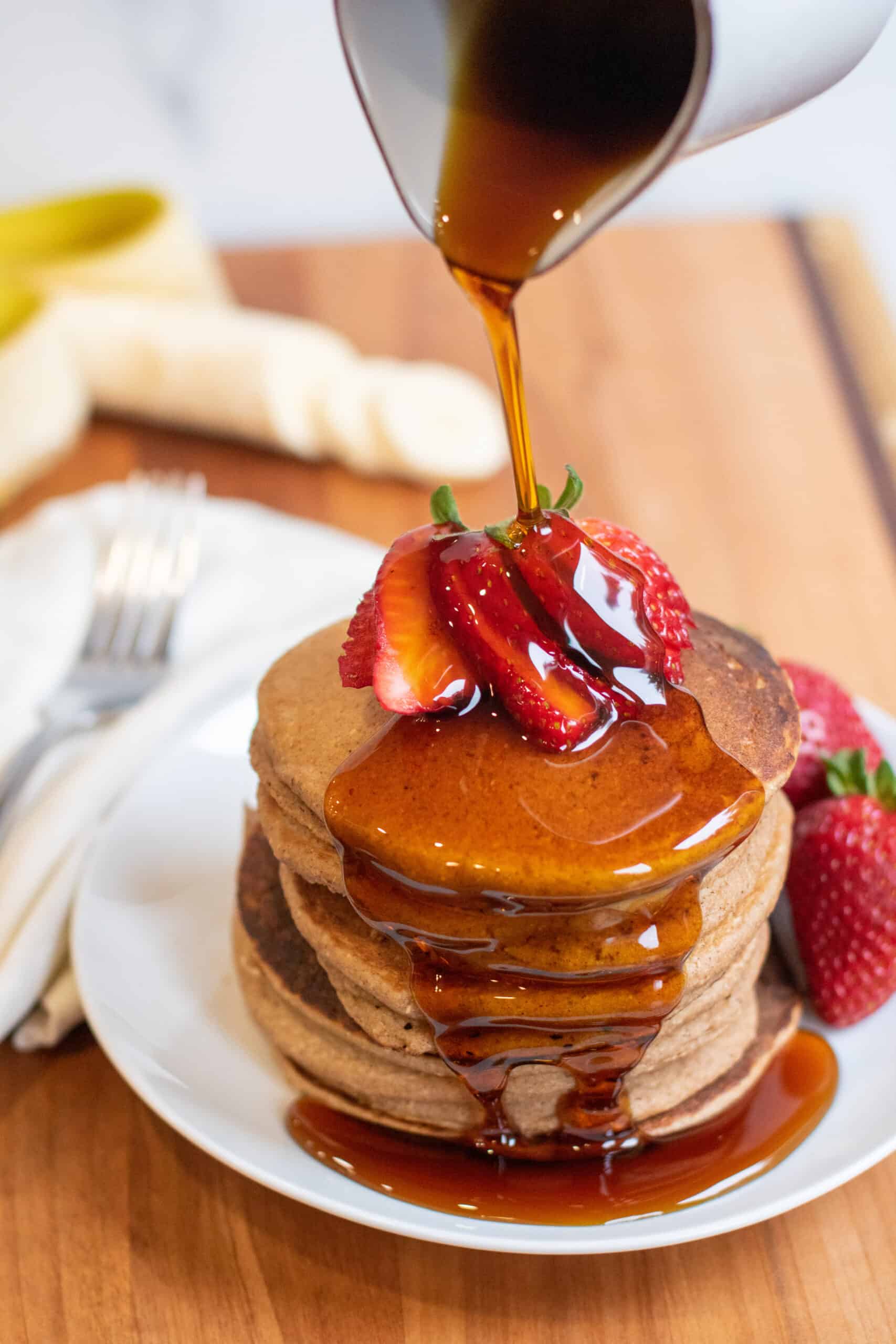 a stack of pancakes with syrup being poured on.