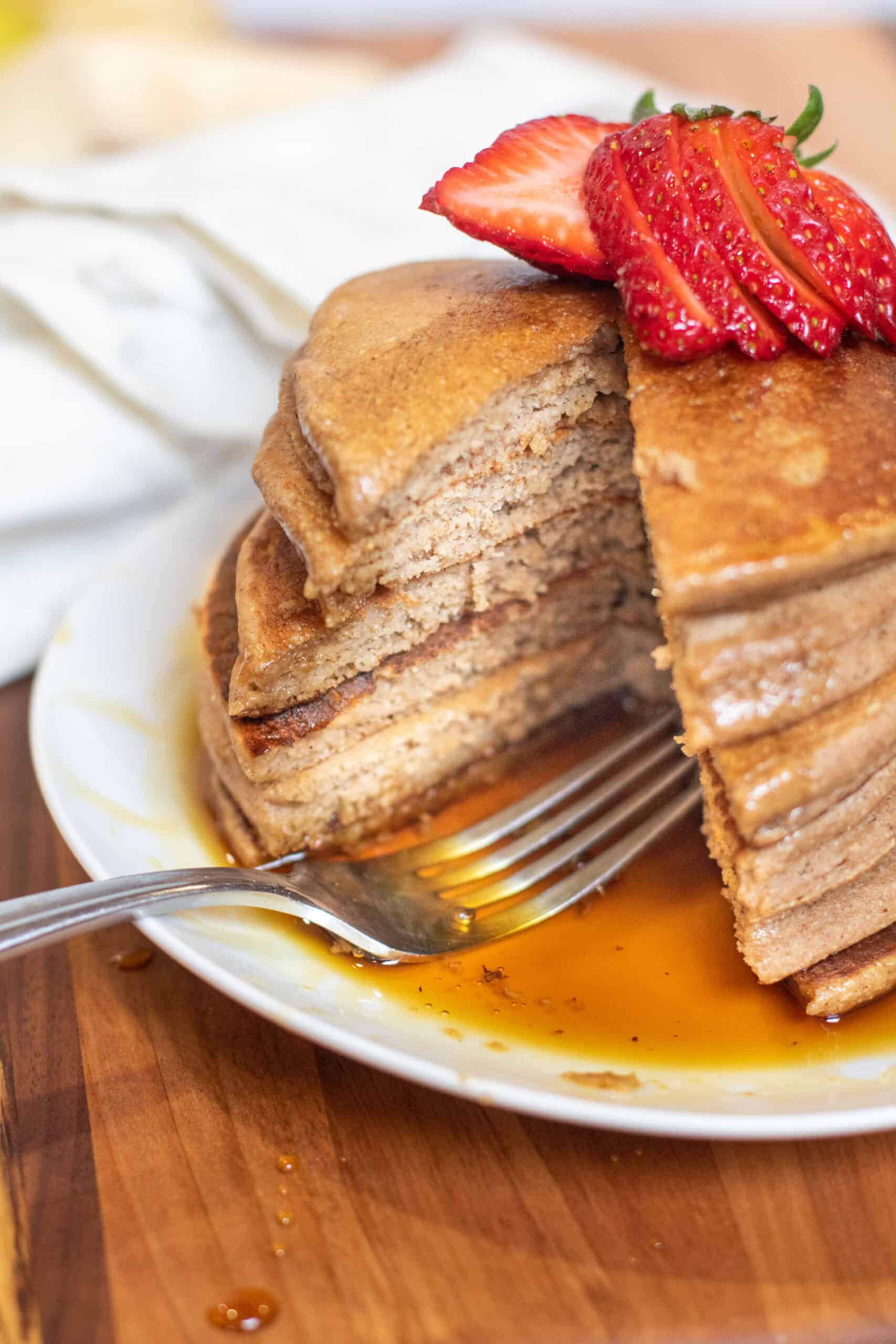 a stack of pancakes with a piece cut out and a fork.