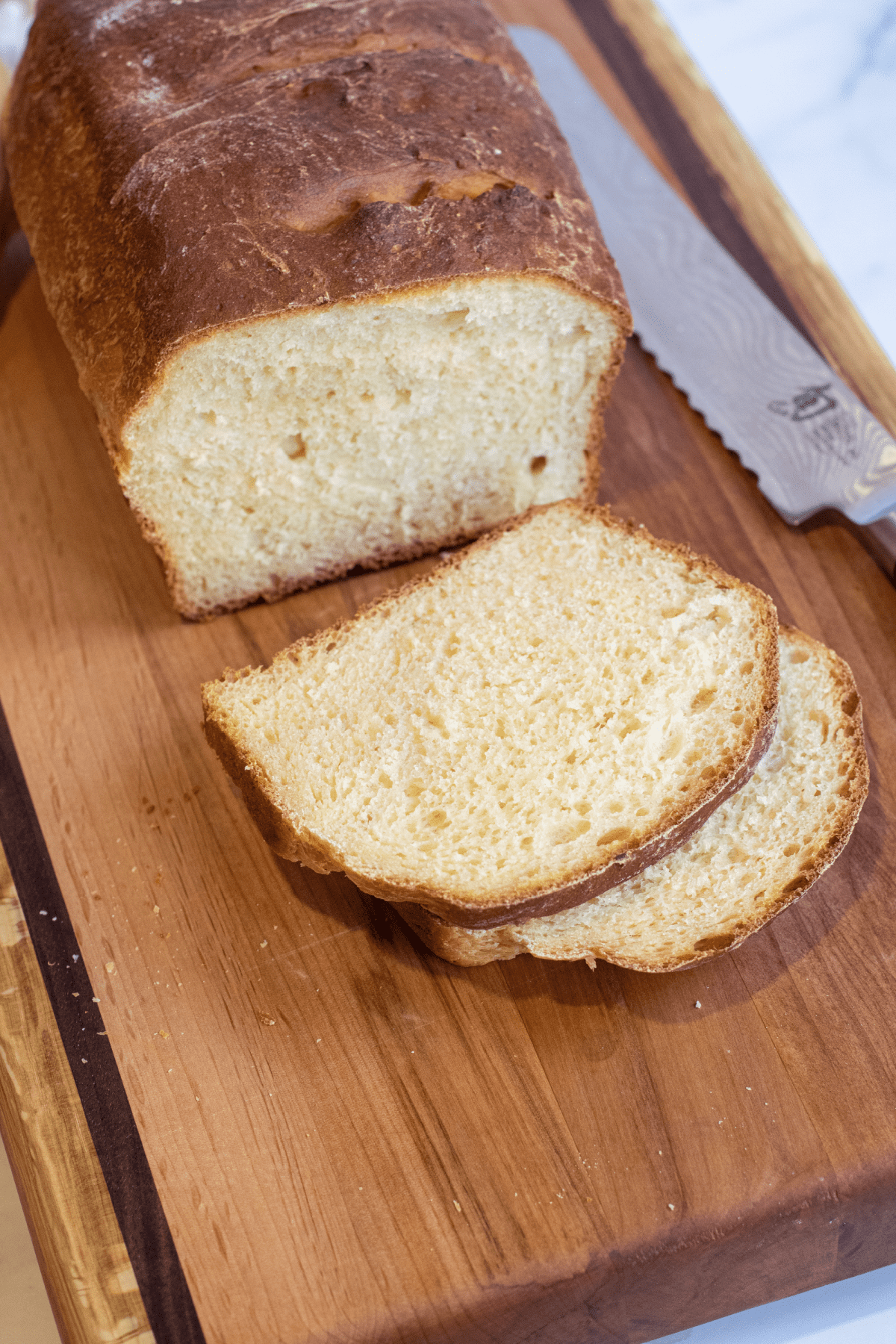 a loaf of bread on a cutting board with two slices.