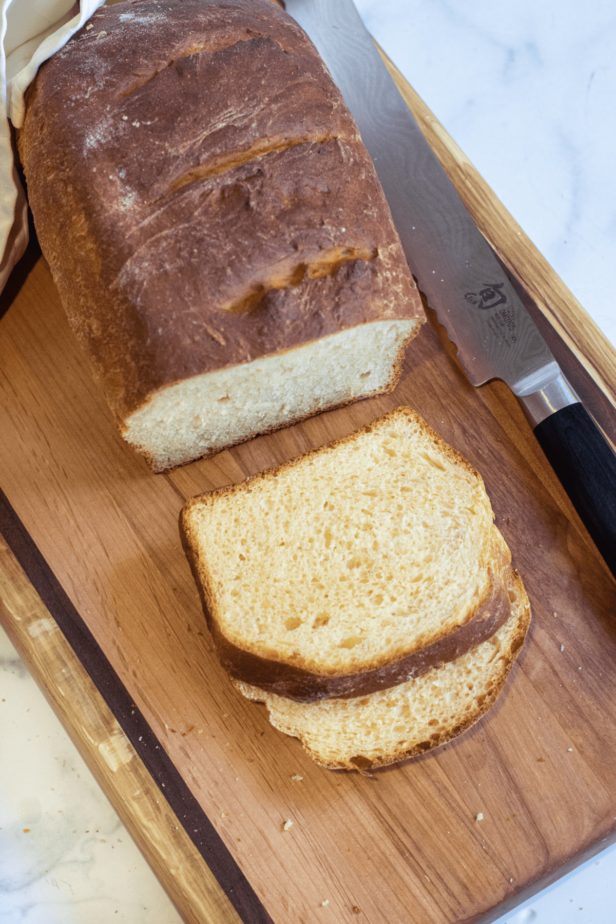 a loaf and sliced bread on a board.