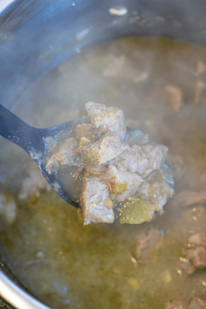 a spoon over an instant pot with a spoonful of pork verde.