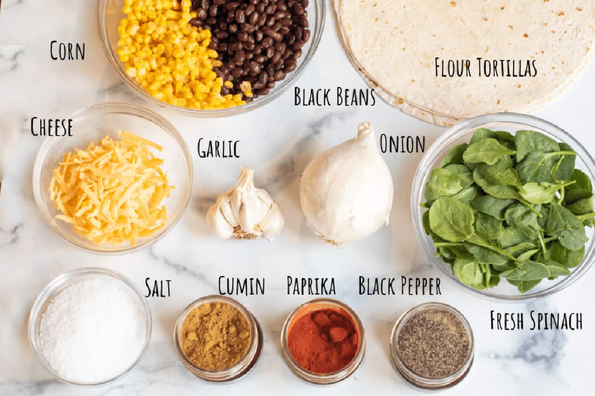 flour tortillas, a bowl of beans and corn, onion, shredded cheese, spices, fresh spinach, and flour tortillas.