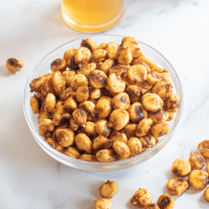 a bowl of corn nuts with some spilled.