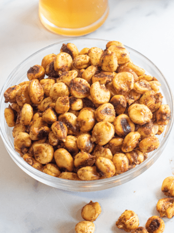 a bowl of corn nuts with some spilled.