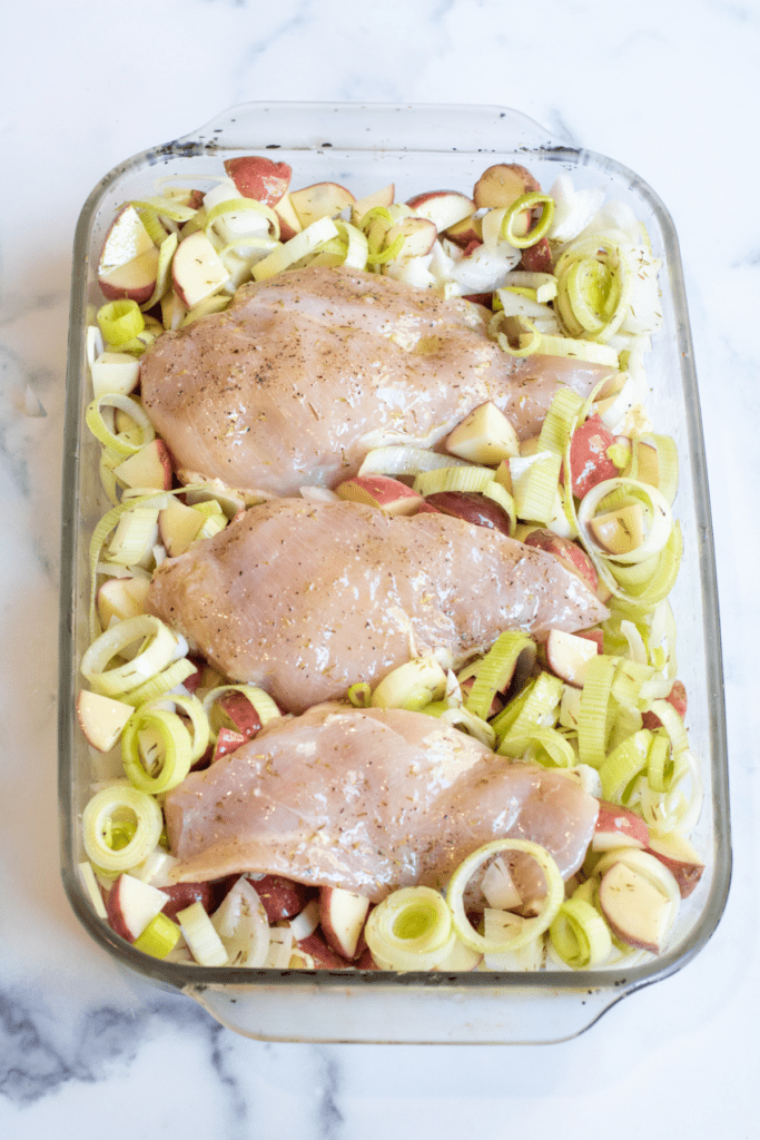 a pan with raw chicken, potatoes, leeks.