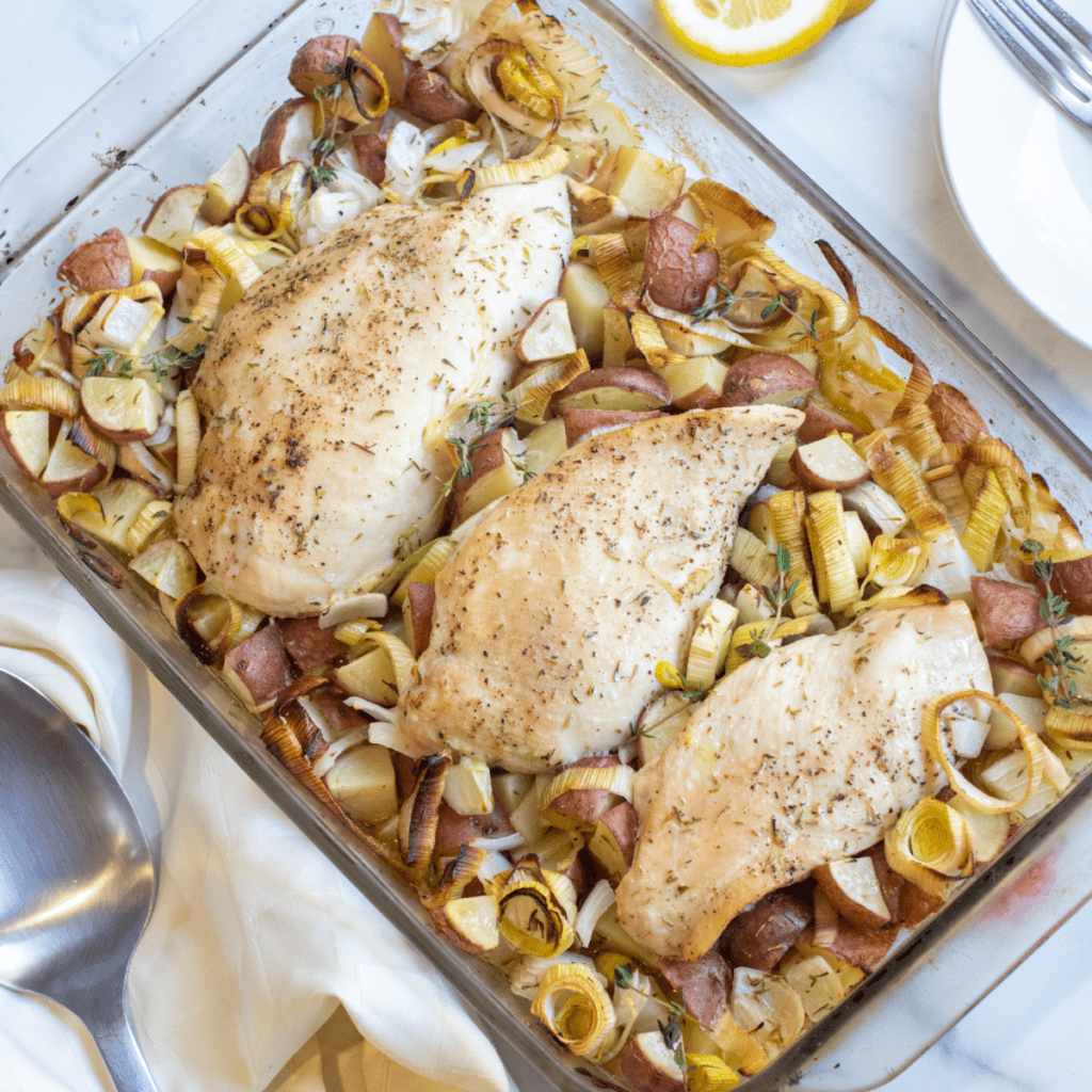 a pan of baked chicken with potatoes, leeks. 