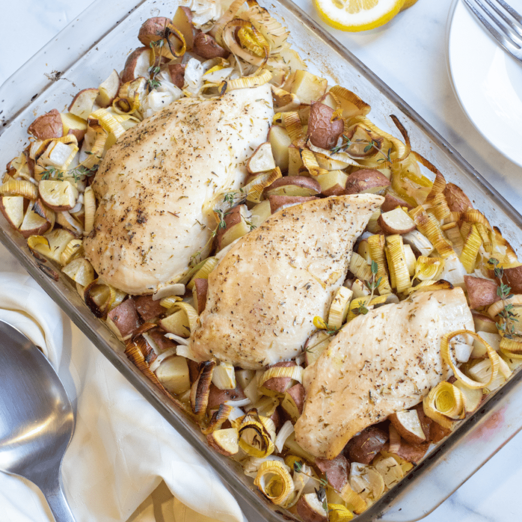 a pan of baked chicken with potatoes, leeks.
