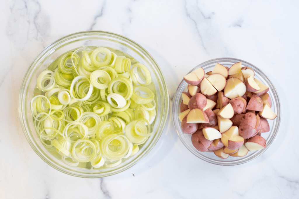 a bowl of sliced leeks in water and diced potatoes.