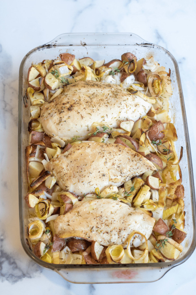 a pan of baked chicken with potatoes, leeks.