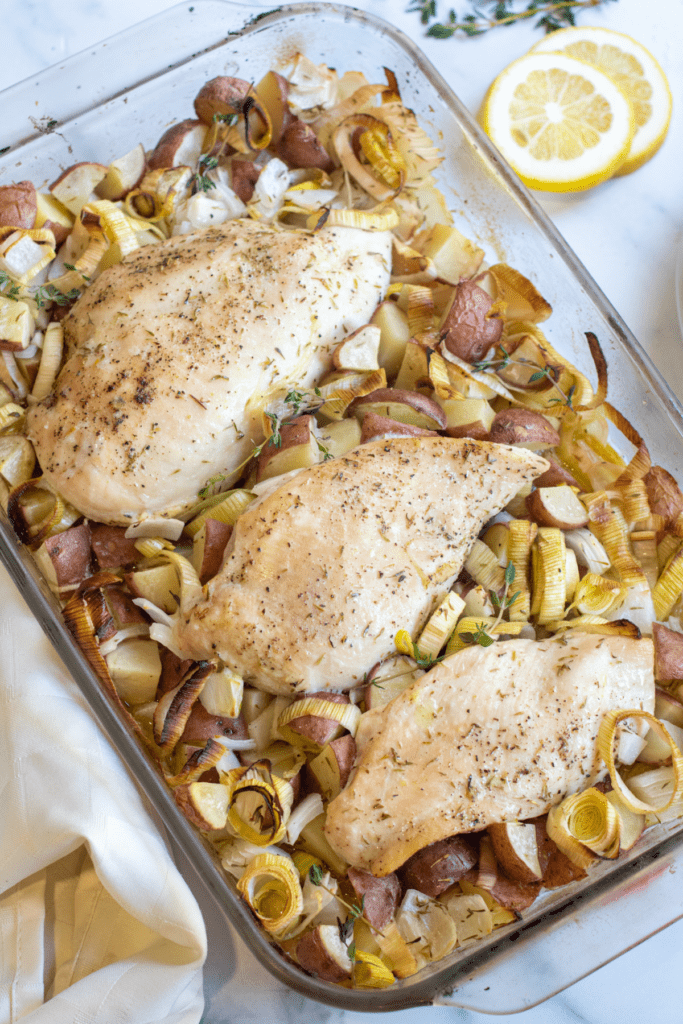 a pan of baked chicken with potatoes, leeks.