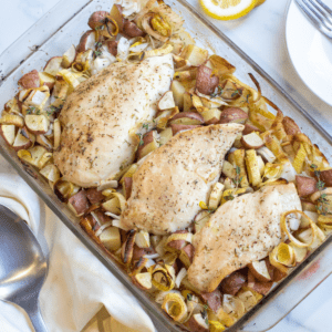 a pan of baked chicken with potatoes, leeks.