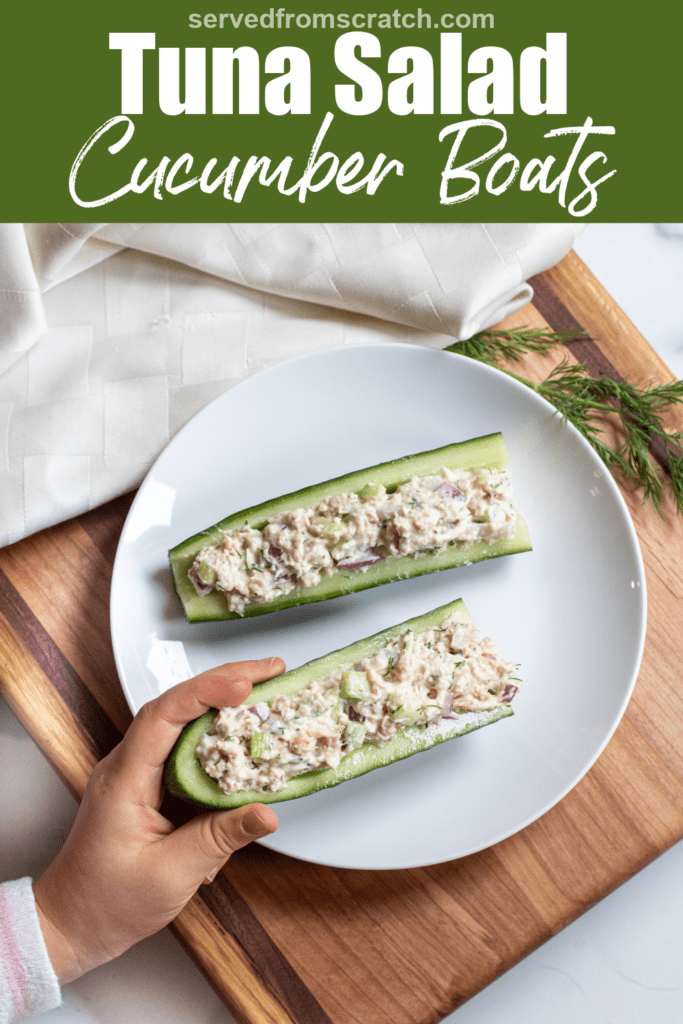 a plate with cucumber boats and tuna salad with a kids hand holding it with Pinterest pin text.