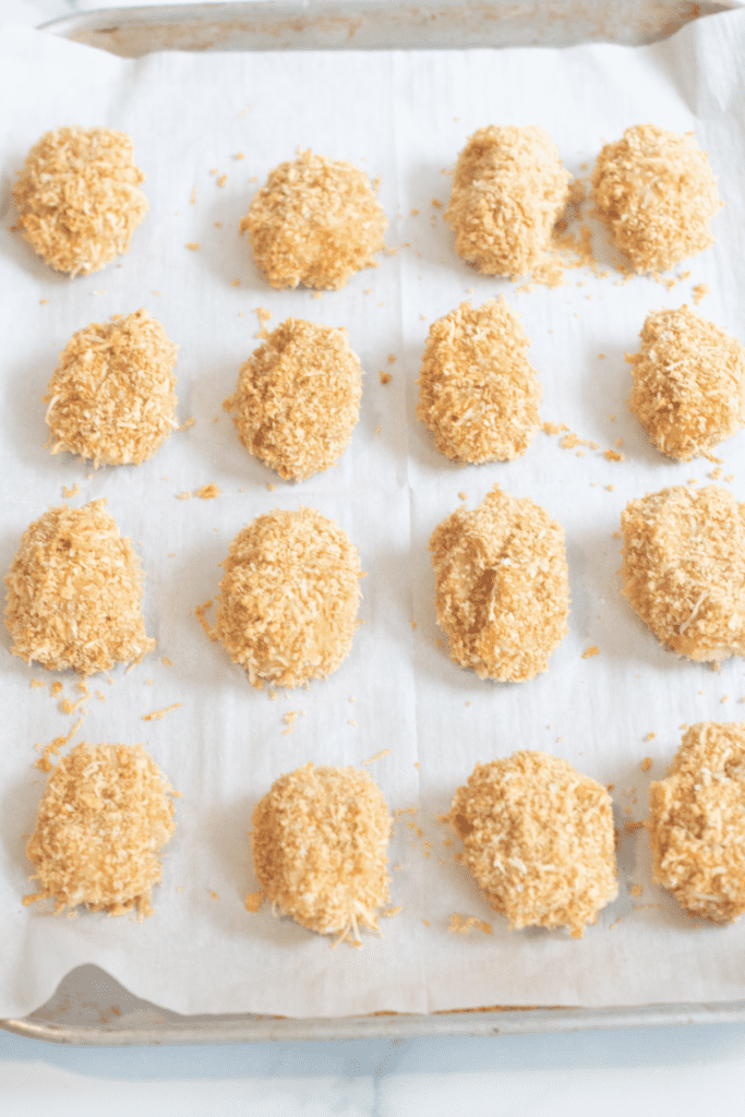 a baking sheet lined with parchment and breaded chicken nuggets.