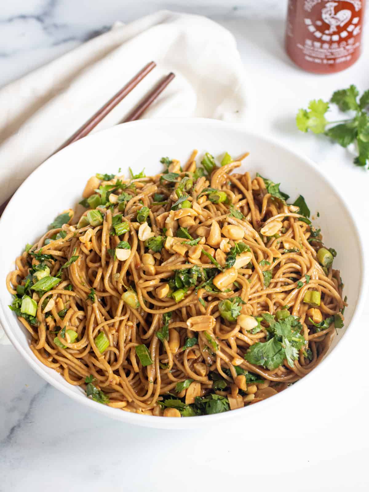 a bowl of noodle with peanuts and cilantro and onions.