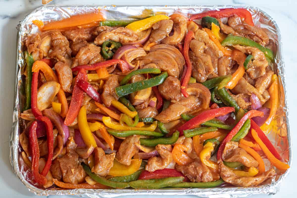 a pan of uncooked chicken fajitas.