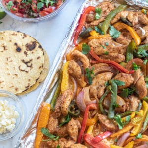 a sheet pan of chicken fajitas, corn tortillas, pico, and cheese.