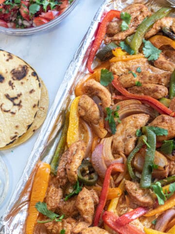 a sheet pan of chicken fajitas, corn tortillas, pico, and cheese.