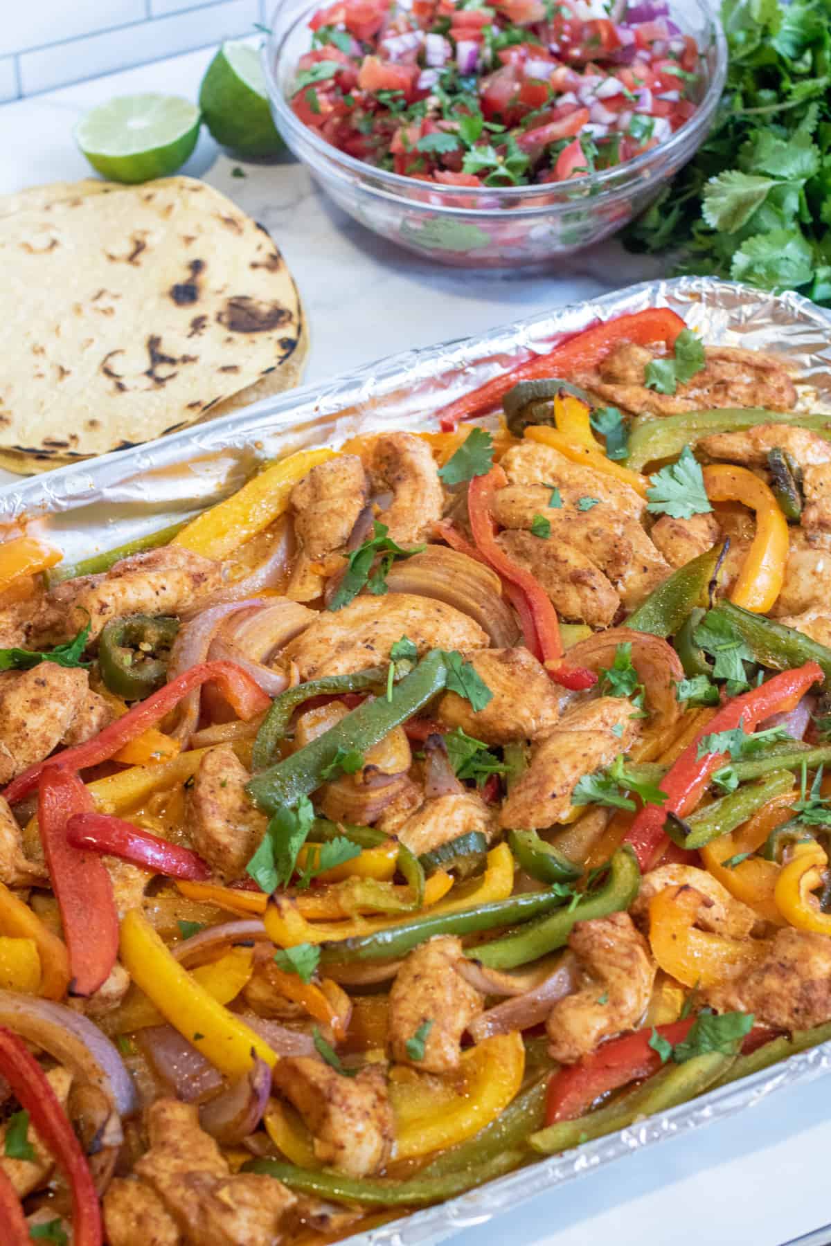 a sheet pan of chicken fajitas, corn tortillas, pico, and cheese.