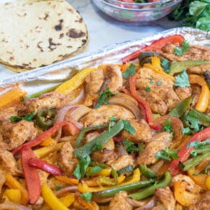 a sheet pan of chicken fajitas, corn tortillas, pico, and cheese.