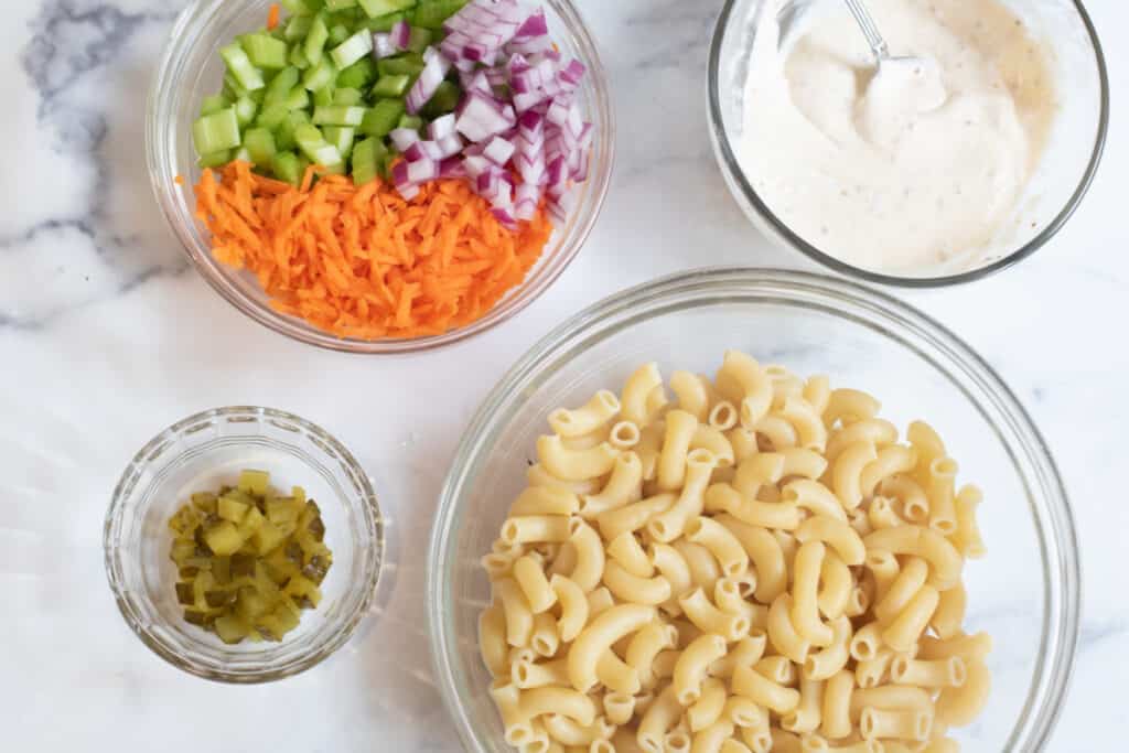 a bowl of macaroni, dill pickles, carrots, celery, onion, and mixed mayo.