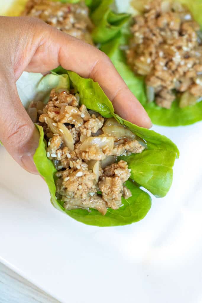 a hand holding a lettuce wrap with ground turkey.