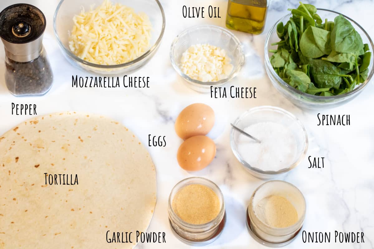 flour tortilla, spinach, cheeses, eggs, olive oil, garlic and onion powder on a counter and labeled. 