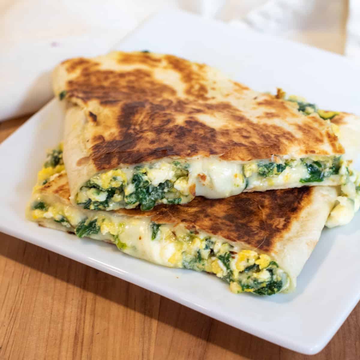 a quesadilla with spinach and cheese on a plate. 