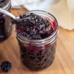 a jar of open blackberry jam with a spoon of jam.