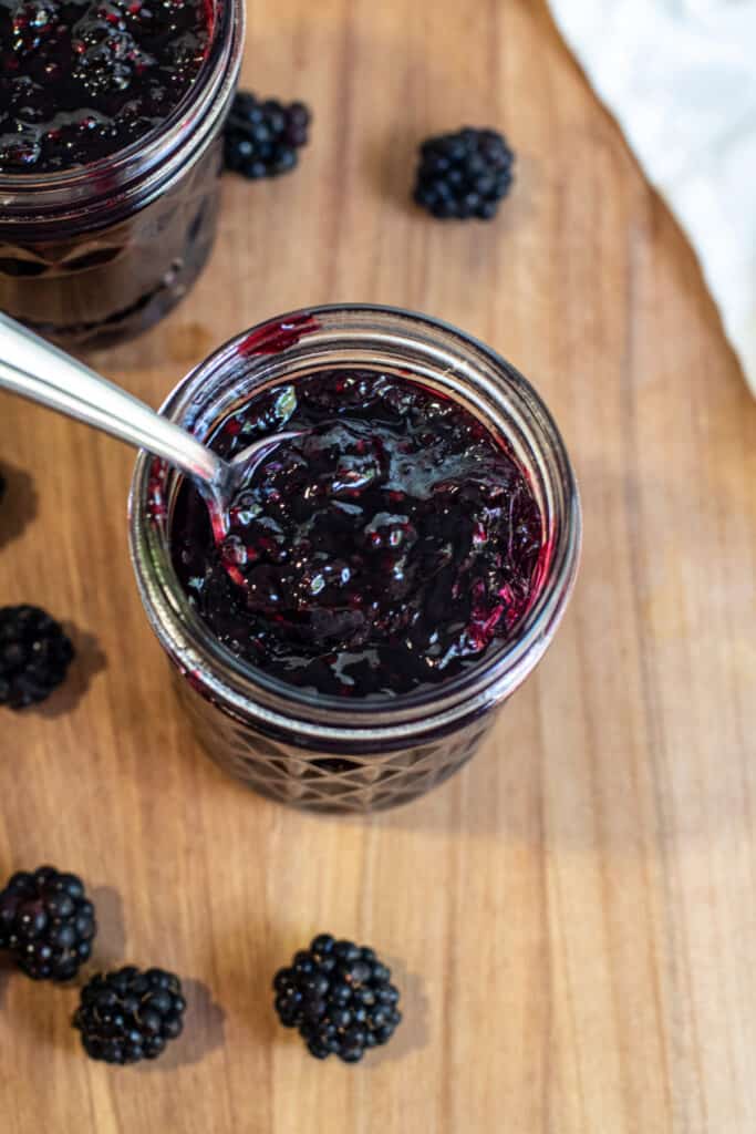 an overhead of an open jar of jam with a spoon in it. 