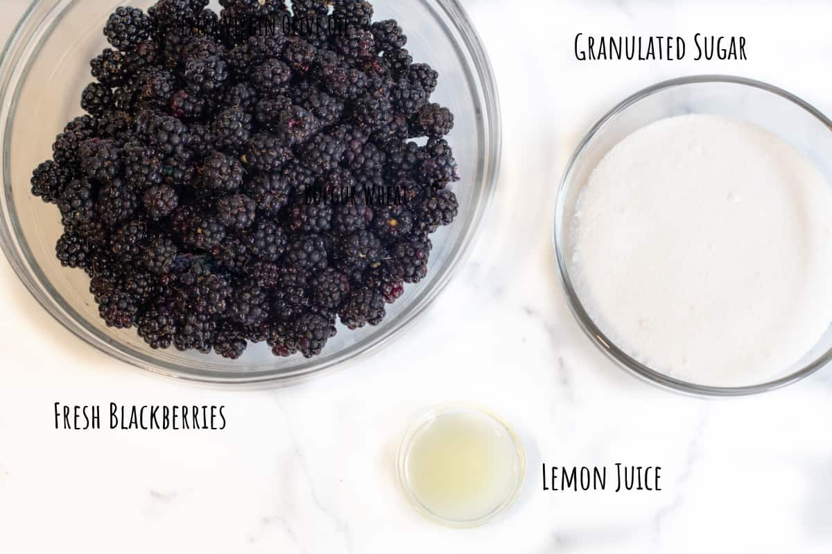 a large bowl of fresh blackberries, sugar, and a small bowl of lemon juice.