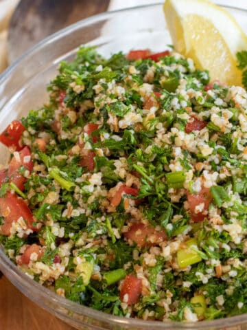 a bowl of tabbouleh with a lemon wedge.