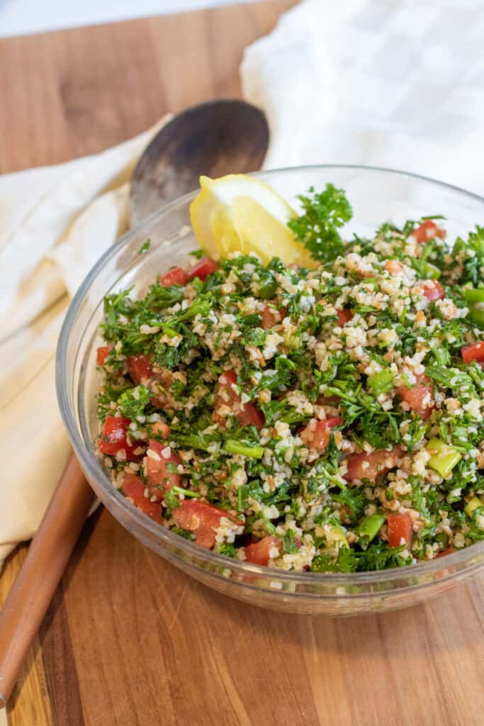 a large bowl of tabbouleh next to a wooden spoon.