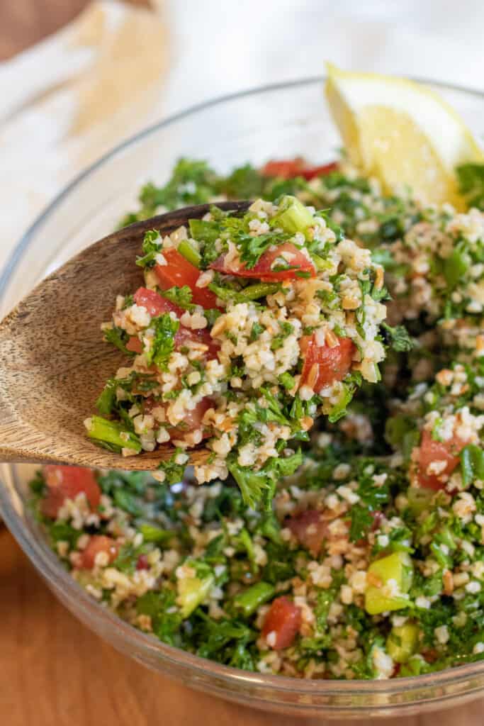 a wooden spoon holding some tabbouleh.
