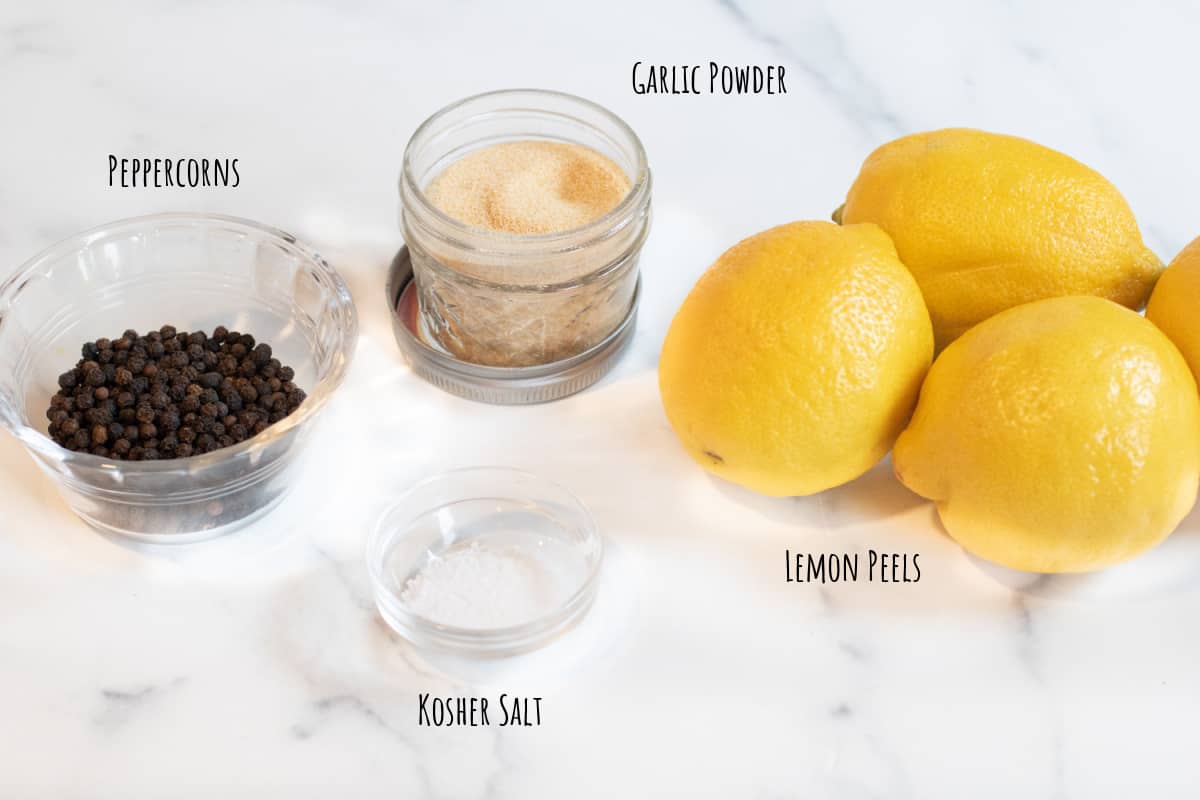 lemons, peppercorns, garlic powder, and salt on a counter.