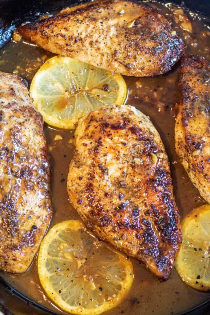 a pan with cooked chicken and sliced lemon slices.