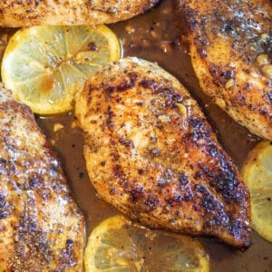 cooked chicken breast with lemon in the pan.