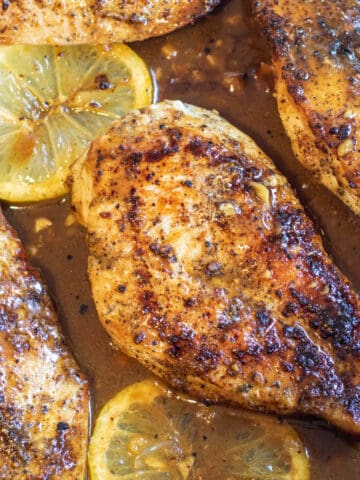 cooked chicken breast with lemon in the pan.