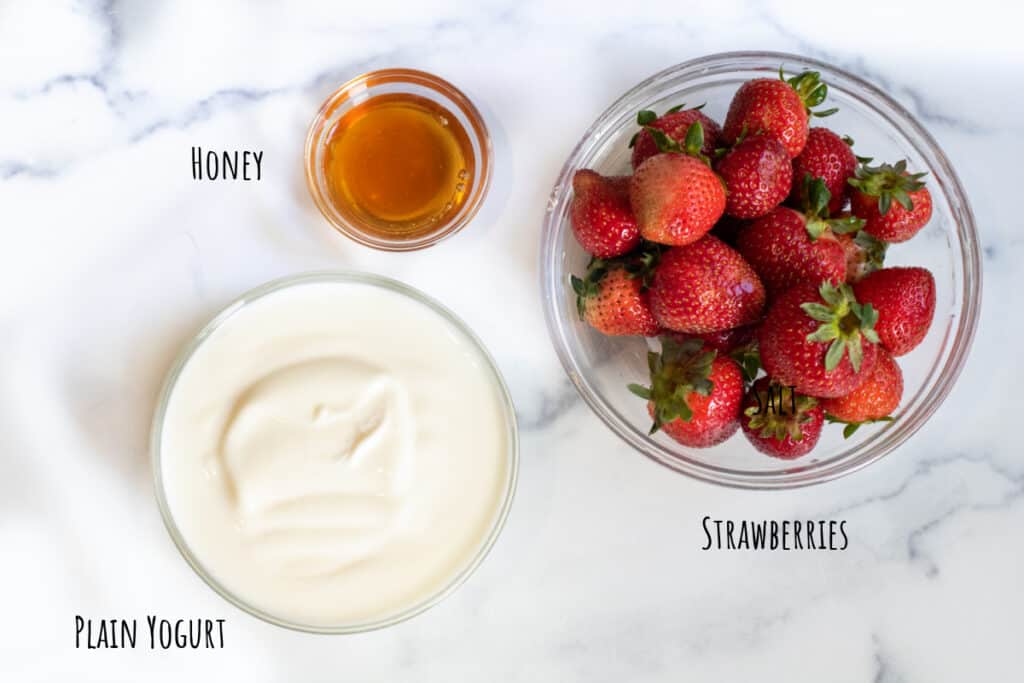 yogurt, honey, and strawberries on a counter.