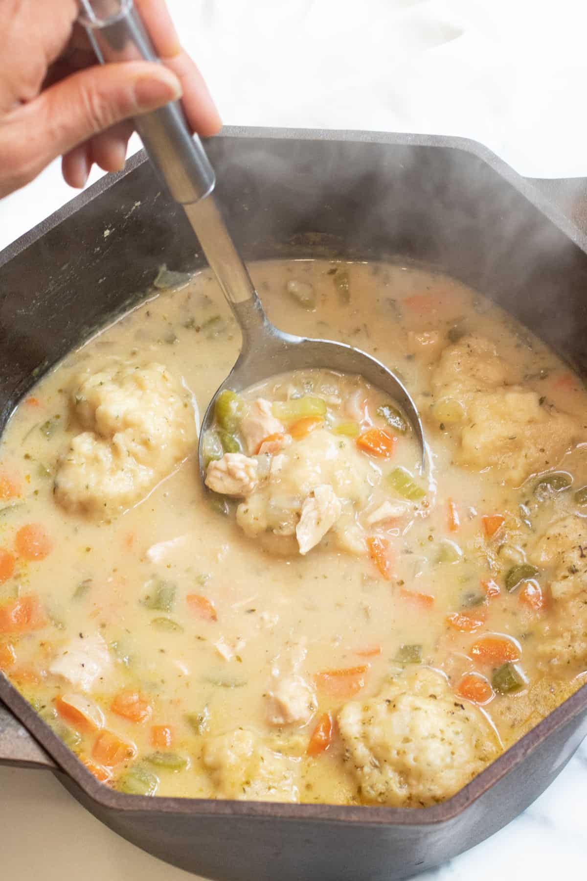 a dutch oven with a creamy chicken and dumplings soup.