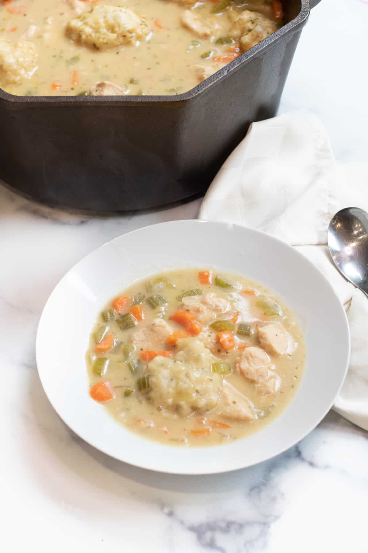 a bowl of soup in front of a dutch oven of soup.