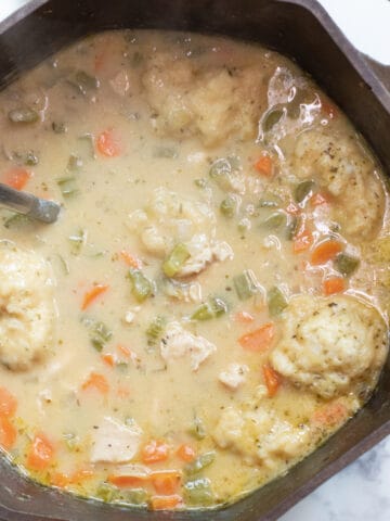 a dutch oven with a creamy chicken and dumplings soup.